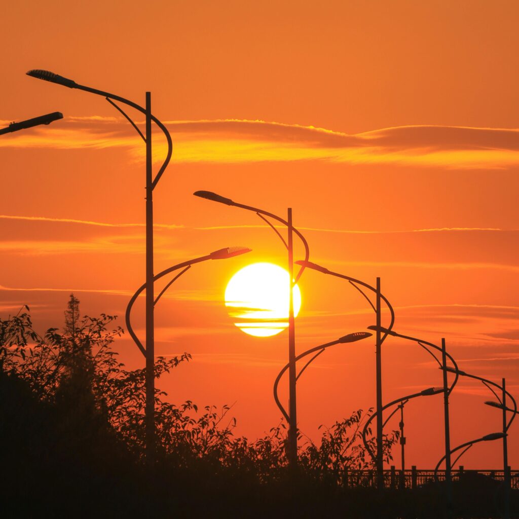 Street lamps against a vibrant orange sunset, creating a silhouette in an urban setting.